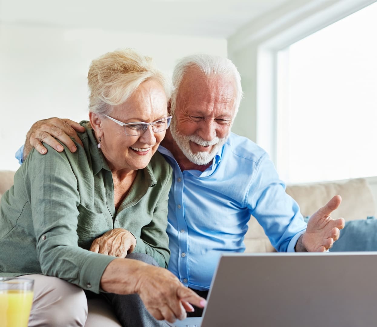 Portrait of a lovely senior mature couple using a laptop together and having fun sitting on sofa at home