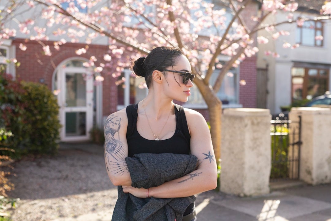 Professionally dressed person stands thoughtfully in front of a sunny, modern suburban home, representing a Tri-Cities lan...