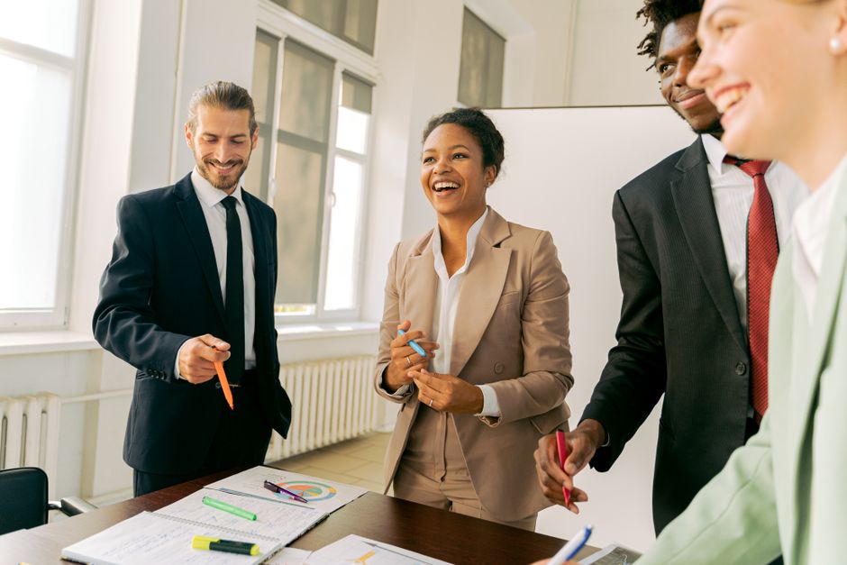Diverse team of professional realtors collaborating around a conference table in a bright, modern office, illustrating tea...