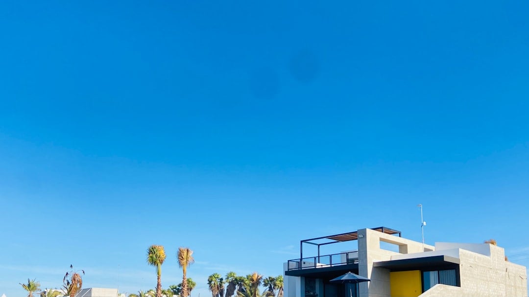 Real estate 'Sold' sign in the front yard of a modern, attractive suburban home under a bright, sunny sky, symbolizing a q...