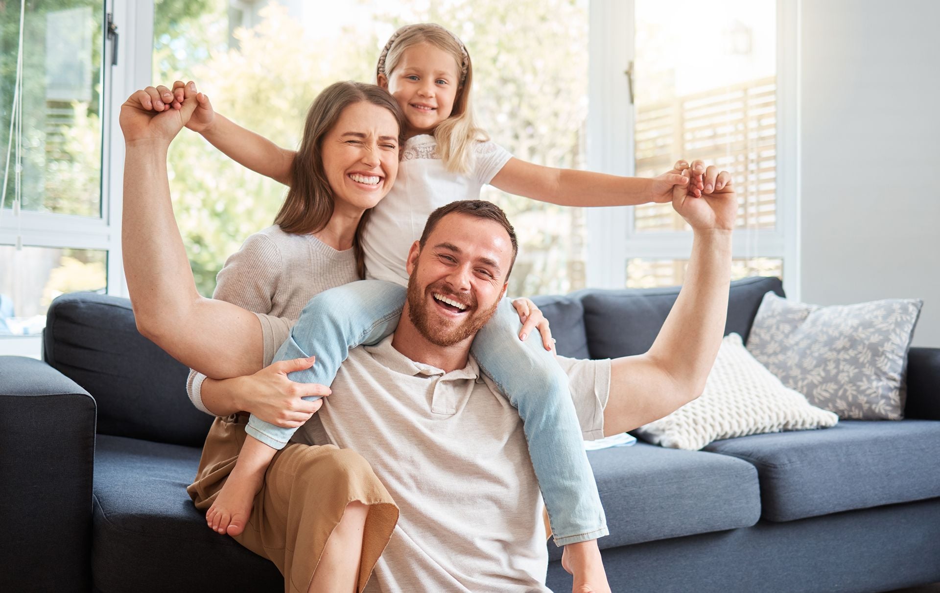 Smile, family and portrait on shoulder by sofa for weekend fun, happiness and bonding together. Playful, mom and dad with daughter in living room for support, care and love at home on fathers day