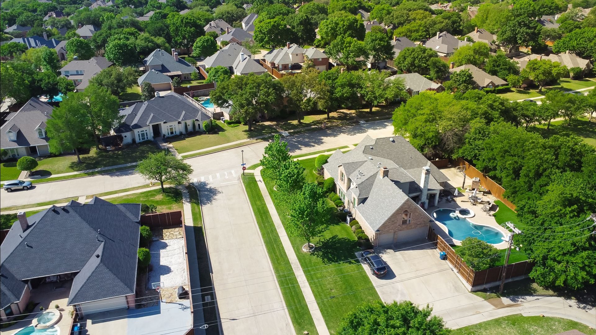 Two story suburban single-family home with swimming pool, large backyard, tall wooden fence in suburb Dallas, Texas subdivision, upscale house lush greenery tree, well-trimmed landscape, aerial. USA 1
