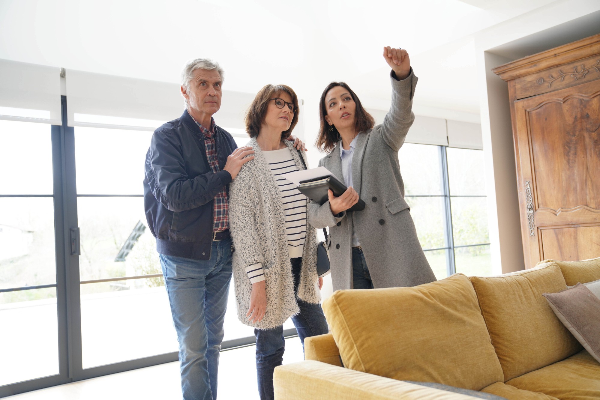 Senior couple with real estate agent visiting contemporary house