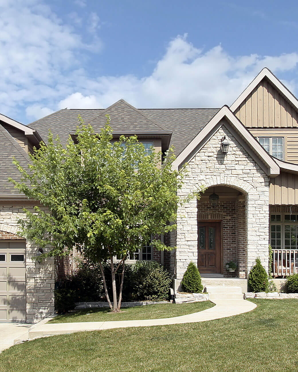 A two-story home with a stone facade and a covered entryway.