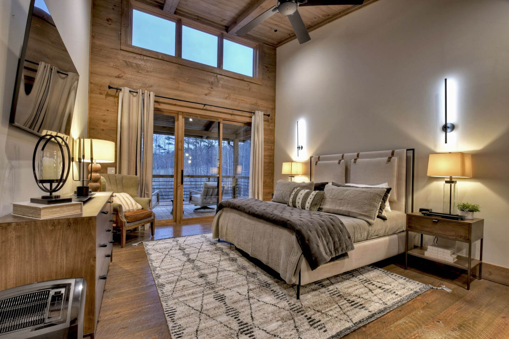 Bedroom with a king-size bed, wood-paneled walls, and a sliding glass door leading to a balcony.