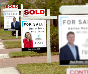 A photo of a house with a "sold" sign in front of it while another similar house is being listed for sale nearby. 3 homes for sale in a neighborhood. Lisa McBride, Sarasota Neighborhood Experts Realtor and Youtuber on the for sale sign
