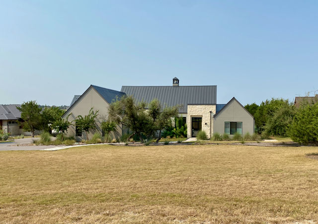 House with tan stucco exterior and black roof.
