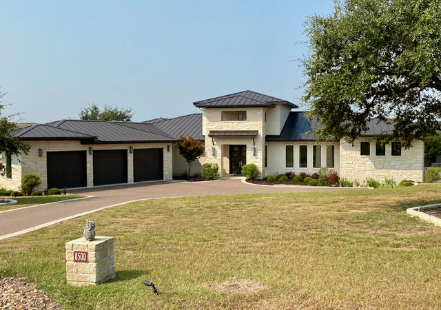 Large home with black roof, three care garage and cream colored exterior.