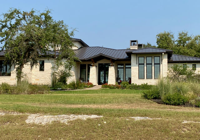 One story limestone house with black roof