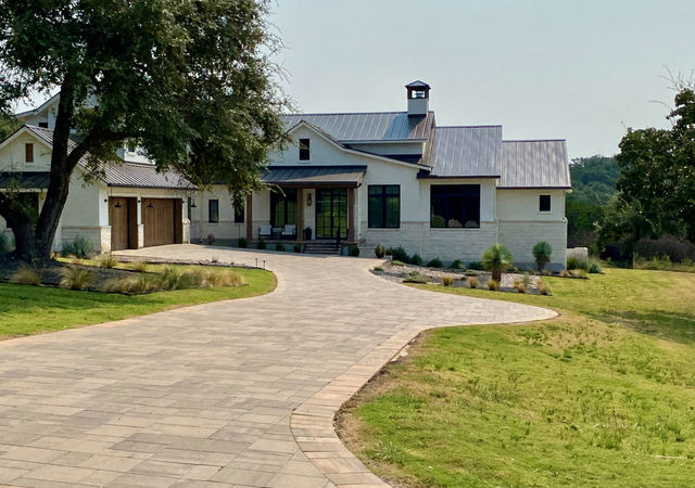 Long drive leading to a house with white exterior.