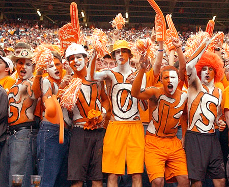 Fans painted in orange & white with "VOLS" spelled out on their chest, yelling and cheering on the University of Tennessee Vols Football Team