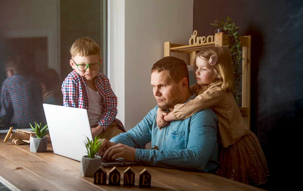 dad on laptop with 2 kids surrounding him