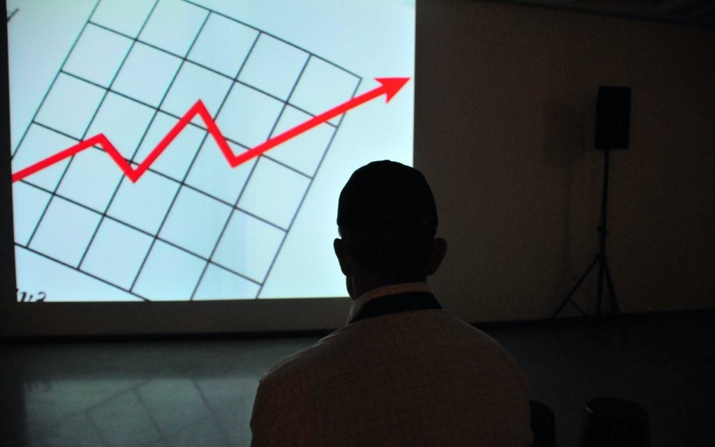 person looks at a graph with an upward arrow