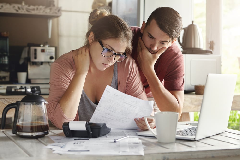Couple look over bills with concerned faces