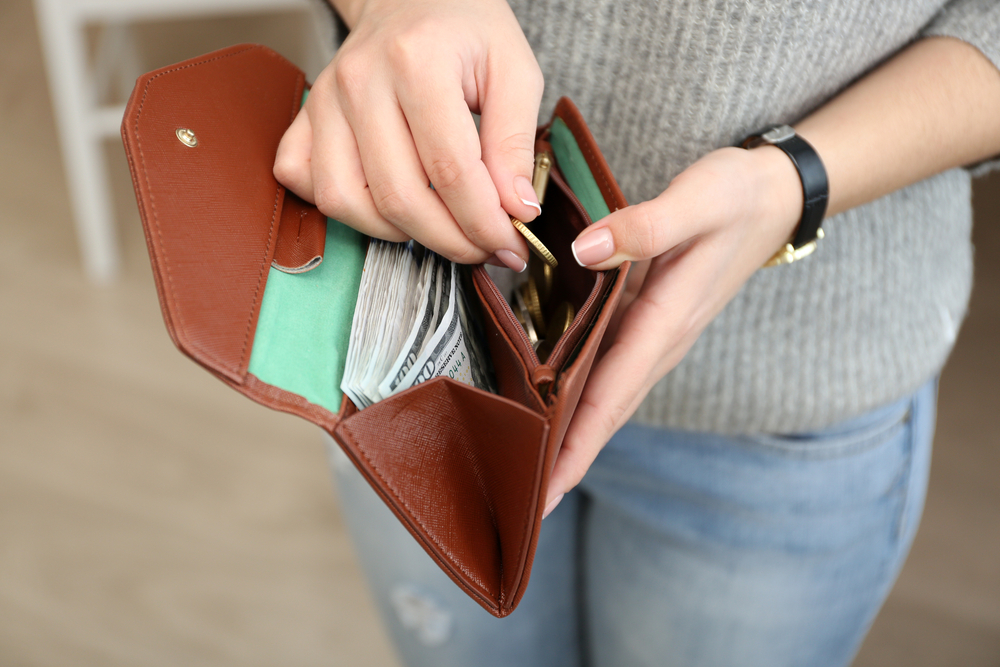 Woman holds open a wallet filled with money