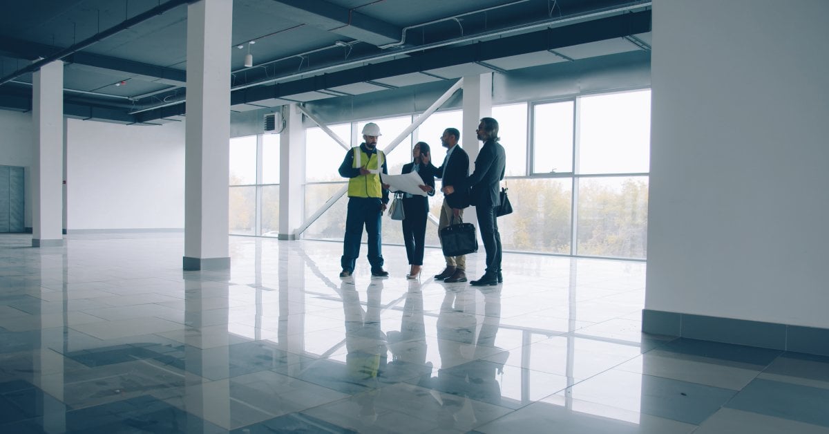 A group of real estate investors meeting with a construction worker at their new construction project site.