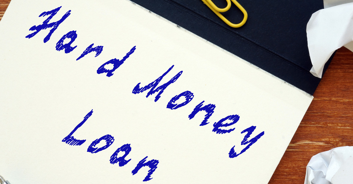 A notepad on a desk with the words “Hard Money Loan” scribbled on the paper in blue ink, next to crumpled-up notes.