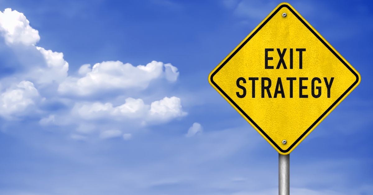 A yellow diamond-shaped road sign displaying "EXIT STRATEGY" in black text while a blue sky with clouds is in the background.