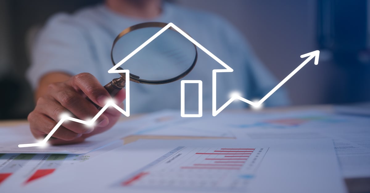 A person examining paper charts using a magnifying glass while a glowing house icon with arrows hovers above the table.