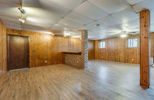 lower level den, brick fireplace, ceiling fan, ceiling tiles, brick and wood accents