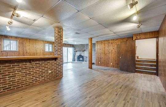 lower level den, brick fireplace, ceiling fan, ceiling tiles, brick and wood accents, entrace/exit