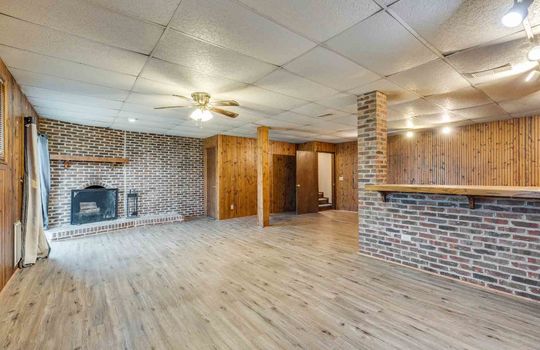 lower level den, brick fireplace, ceiling fan, ceiling tiles, brick and wood accents