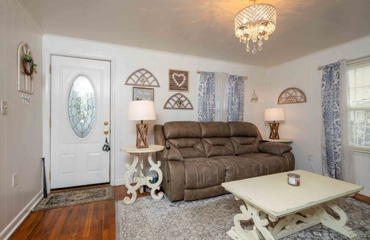 front door, light fixture, chandelier, window, hardwood flooring, living room