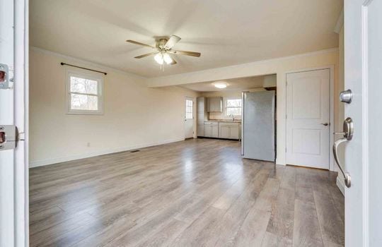 Living room, hallway, vinyl flooring, ceiling fan, windows, front door, view into kitchen