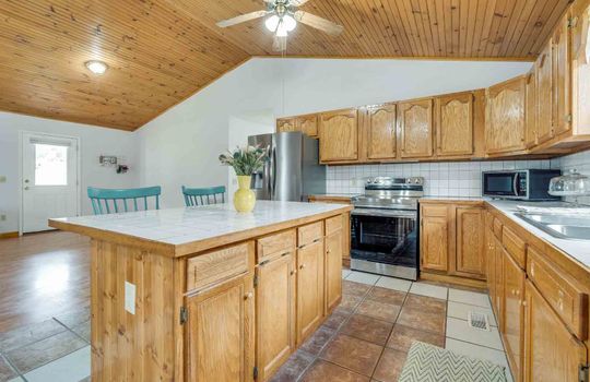 kitchen, kitchen island, tile flooring, cabinets, stove, refrigerator, vaulted wood ceiling, tile backsplash
