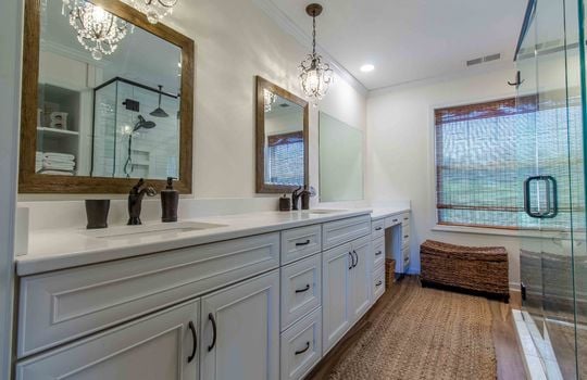 primary bath, double sink, cabinets, vanity, chandeliers, glass door to tile shower