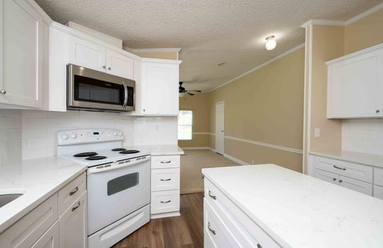 kitchen, kitchen island, white cabinets, stove, microwave