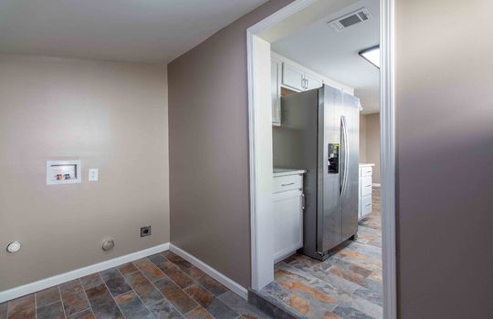 laundry area, door to kitchen, tile flooring, kitchen, refrigerator