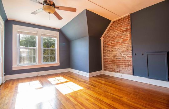bedroom, brick feature wall, hardwood flooring, window, ceiling fan