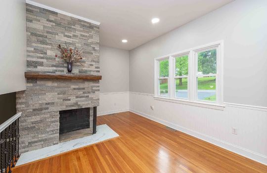 Living room, stone fireplace, hardwood flooring, recessed lighting, window