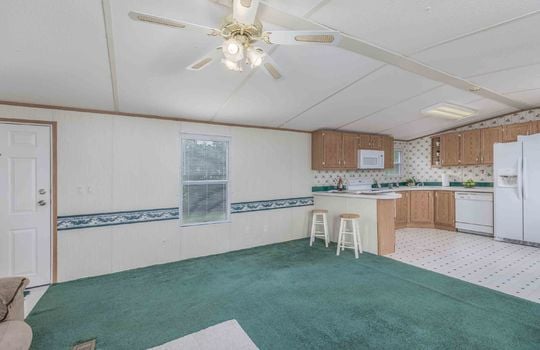 open floorplan living room into kitchen, carpet, ceiling fan, kitchen bar