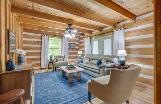 living room, log walls, wood ceiling, ceiling fan, windows, wood flooring