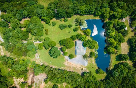 aerial view of property, home, pond, trees