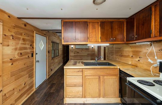 kitchen, exterior door, living room, laminate flooring, paneling walls, kitchen cabinets, sink