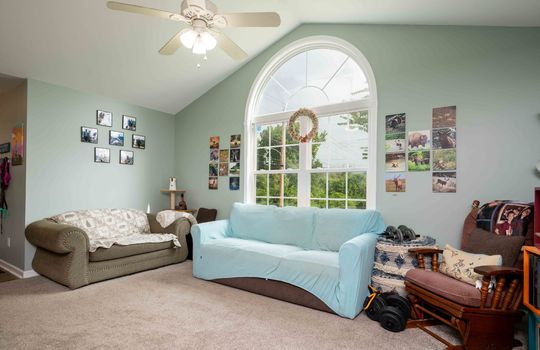 living room, carpet, large arched window, ceiling fan