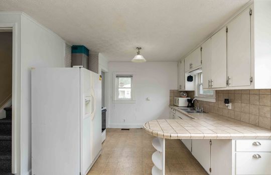 kitchen, laminate flooring, bar counter, tile counter, refrigerator, stove, sink, cabinets, windows