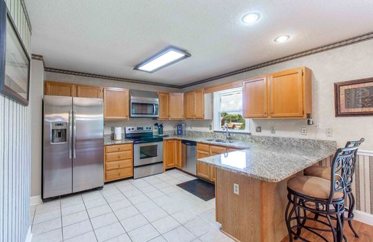 kitchen, cabinets, granite countertops, bar seating, window, refrigerator, stove, microwave, dishwasher