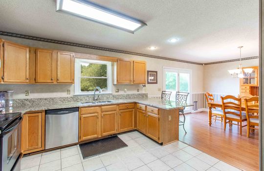 kitchen, tile flooring, cabinets, granite countertops, sink, dishwasher, window, dining area, door to back deck.