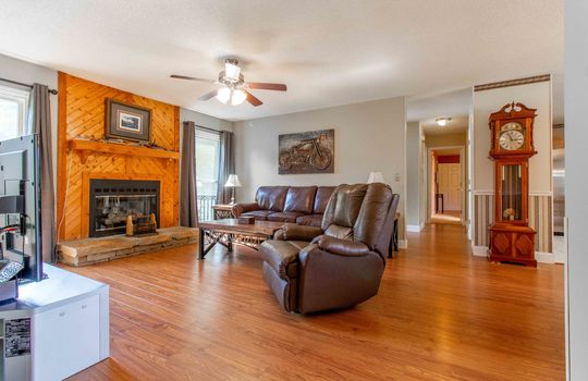 living room, laminate flooring, ceiling fan, wood fireplace