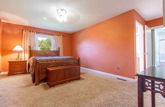primary bedroom, door to ensuite bath, carpet, ceiling fan, window