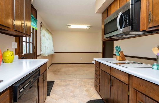 kitchen, cabinet,s countertops, stainless microwave, dining area, vinyl flooring, door to back deck