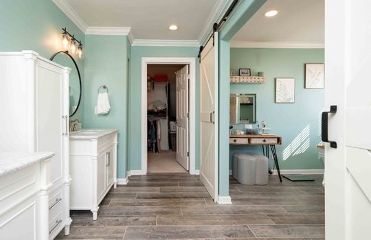 primary bathroom view into walk-in closet, sinks, tile flooring, sliding barn doors