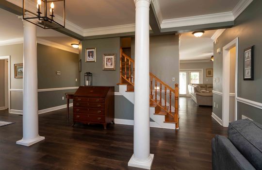 entryway view of stairs and into living room, columns, wainscoting,