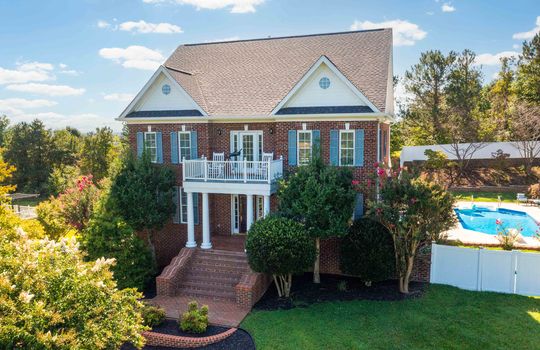 3 Story, Brick, Traditional home. brick, columns, fencing, landscaping, in-ground pool, balcony, trees, front yard, brick steps