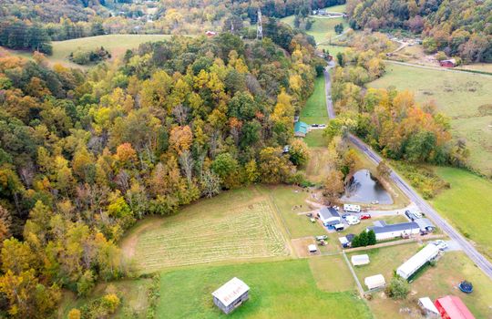 aerial view of property, fenced pasture, wooded area, singlewide, pond, two bay garage