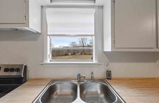 sink, window above sink, view of back yard, countertop, cabinets
